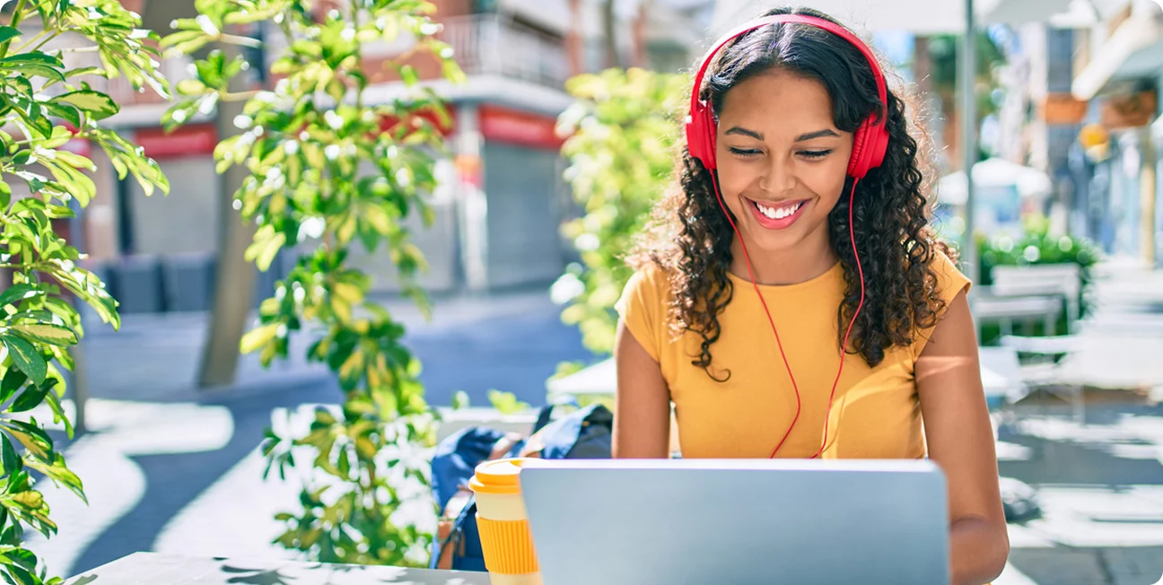 Student wearing a red pair of headphones while using her laptop